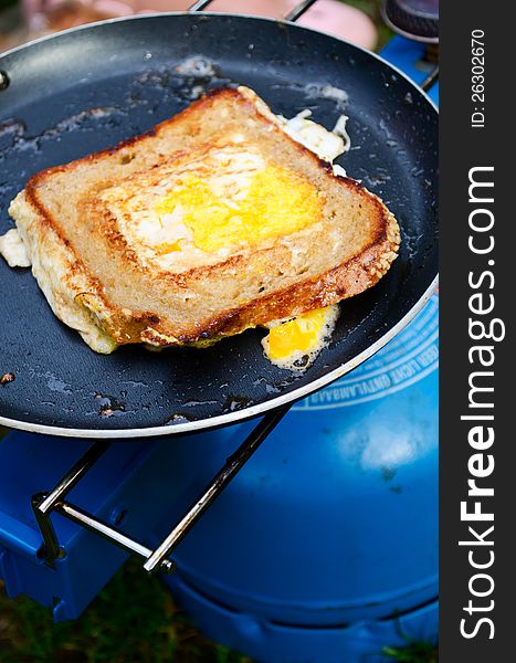 Fried egg sandwich cooking on a simple camp stove. Fried egg sandwich cooking on a simple camp stove