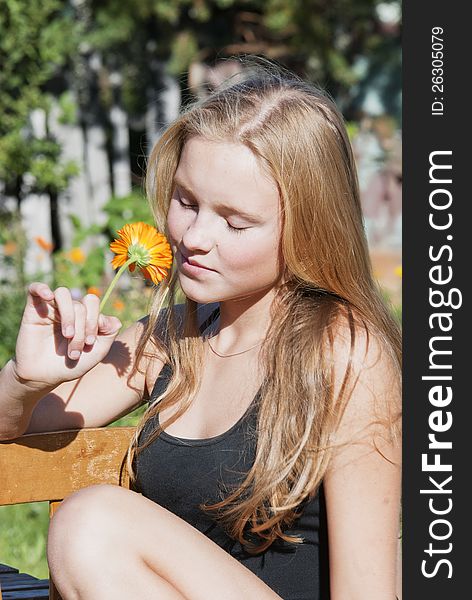 The young girl in a bathing suit on a summer lawn holds a flower. The young girl in a bathing suit on a summer lawn holds a flower