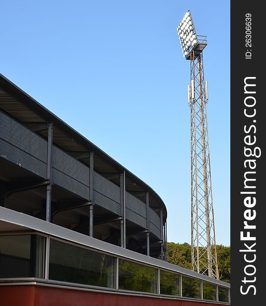 A turned-on light mast at stadium against the blue sky. A turned-on light mast at stadium against the blue sky