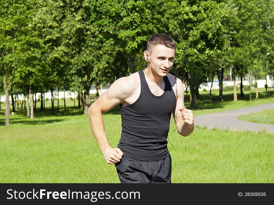 Guy athlete running with headphones in the park