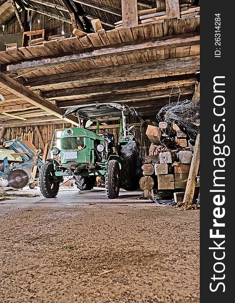 An old tractor standing inside an old barn