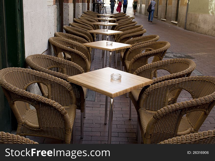 Tables and wicker chairs by bar in the street
