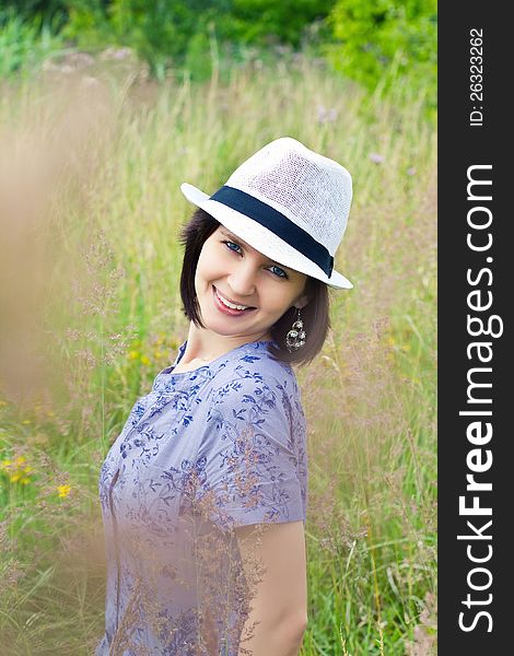 Beautiful young girl in straw hat on the meadow