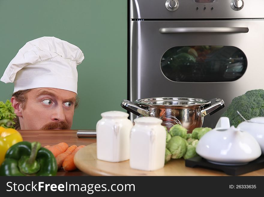 Funny young chef strange looking at pot