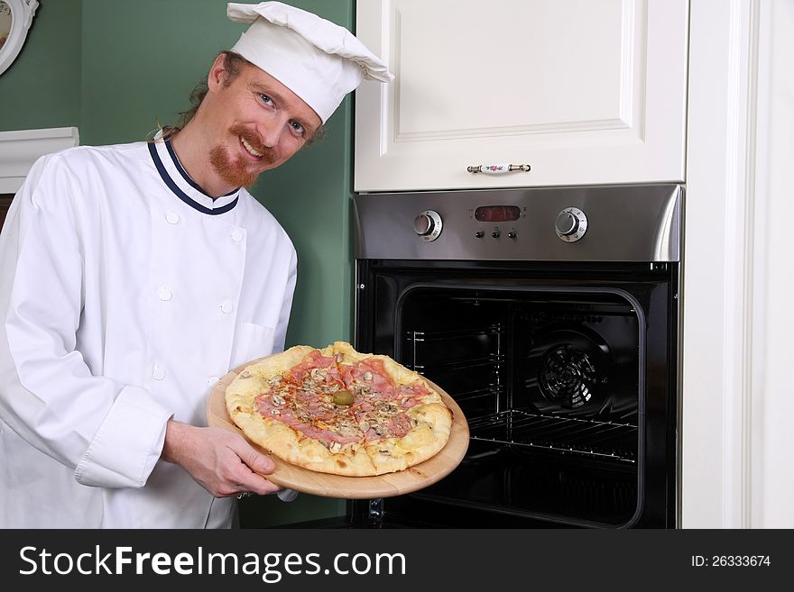 Young chef with italian pizza in kitchen