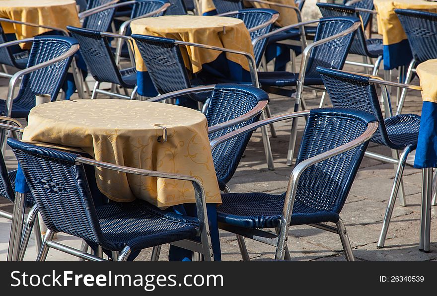 Image of a beautiful and bicolor Venetian street restaurant terrace with rattan chairs.