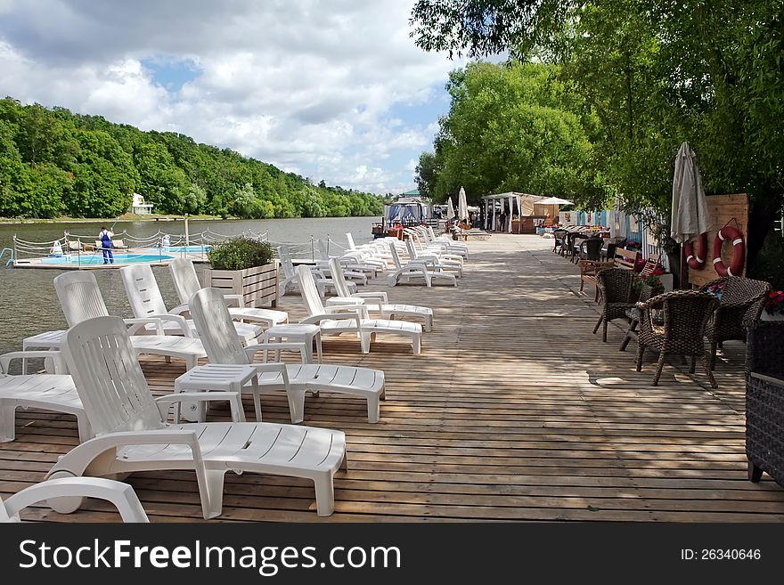 A Lounge chairs on a wooden pier on the river. A Lounge chairs on a wooden pier on the river