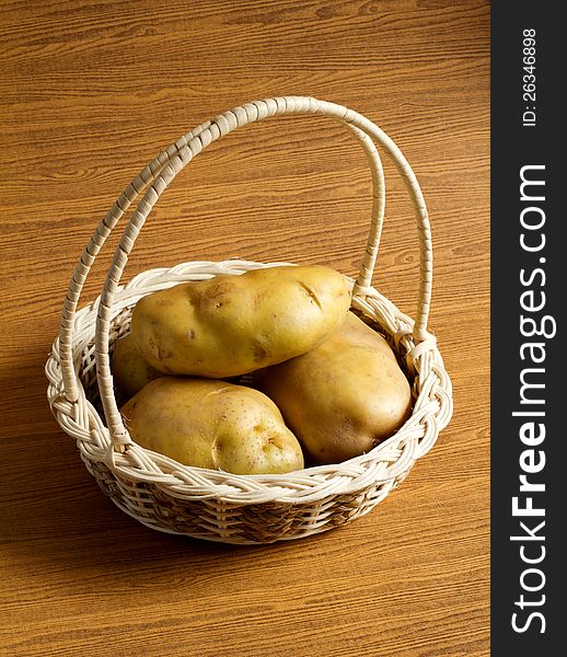 Potatos in the basket on the wood background. Potatos in the basket on the wood background