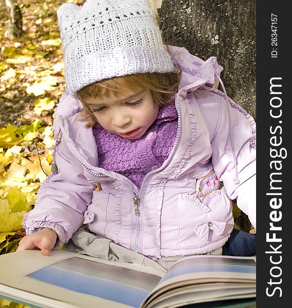 Girl reads a book in an autumn park
