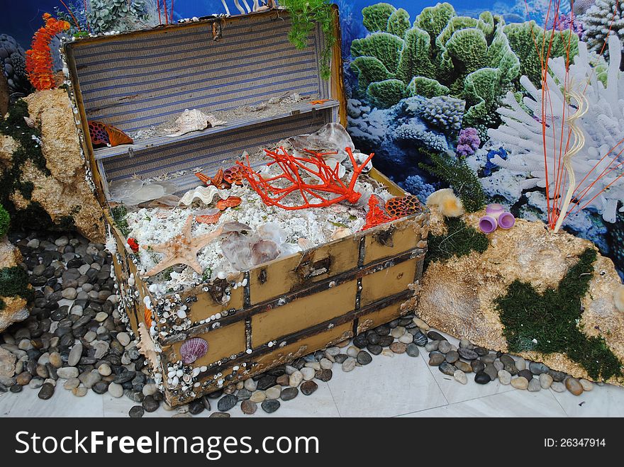 Trunk with treasure, starfishes, sea shels, pebbles against a background with sea and corals