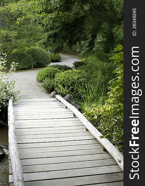 A wooden bridge hidden in the green in a Japanese garden. A wooden bridge hidden in the green in a Japanese garden