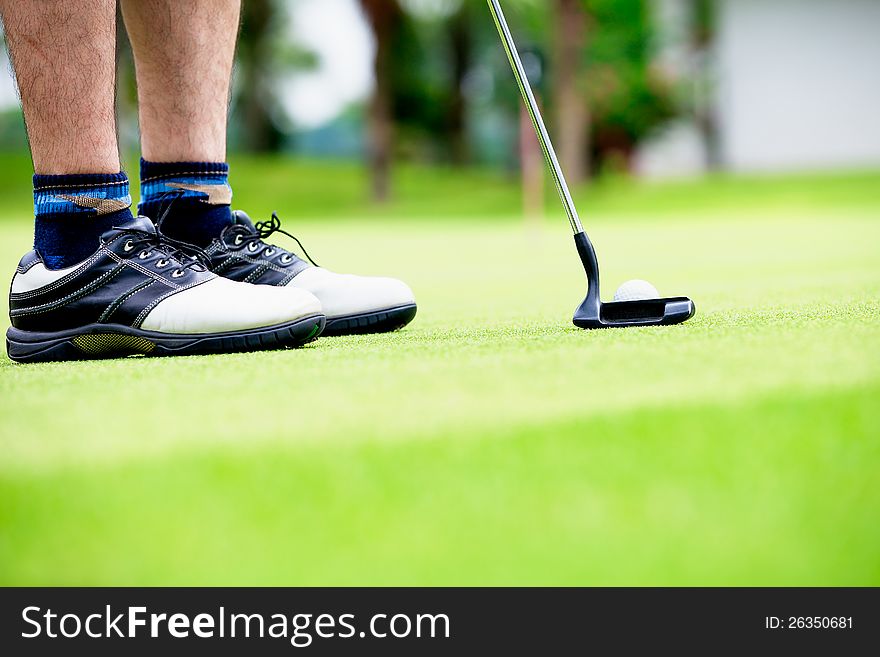 Golfer putting, selective focus on golf ball