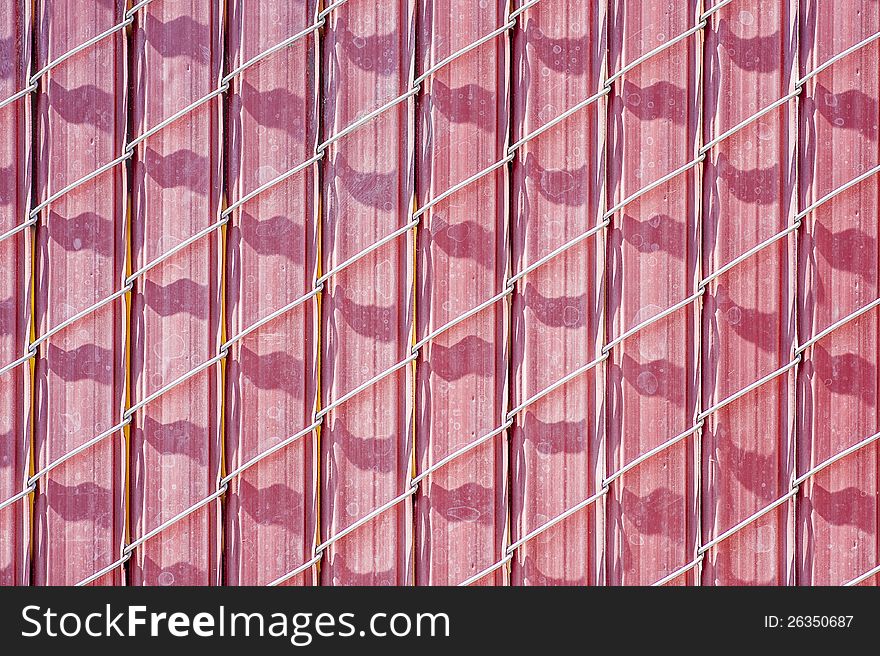 Closeup of pinkish chain link fence with barrier inserts. Closeup of pinkish chain link fence with barrier inserts.