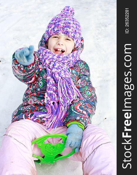 Girl rolls down a hill in winter park