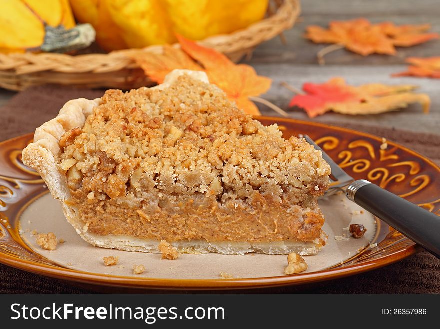 Slice of streusel pumpkin pie with autumn colors in background. Slice of streusel pumpkin pie with autumn colors in background
