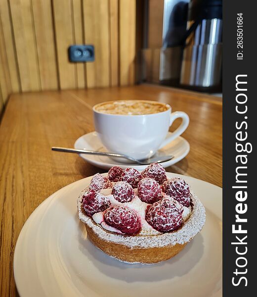 Raspberry Tart On A White Saucer In Front Of A Cup Of Coffee