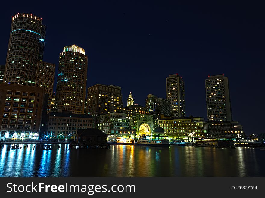 Boston skyline at night with part of the harbor in the foreground. Boston skyline at night with part of the harbor in the foreground