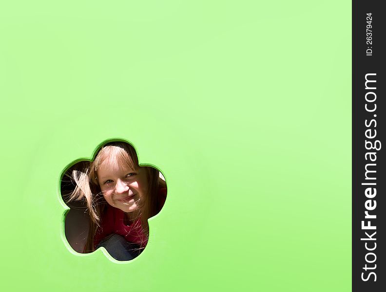 Cute smiling little girl looking through the hole on green background. Cute smiling little girl looking through the hole on green background
