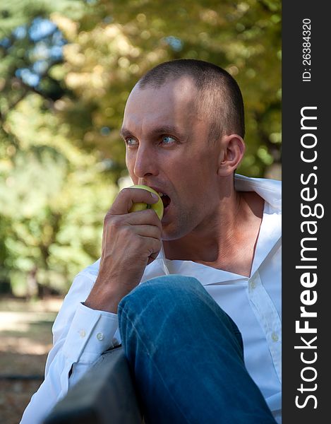 Man relaxing in the park and eating an apple