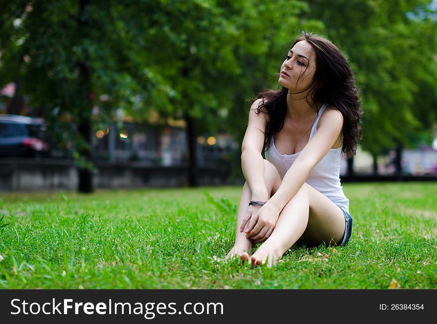 Young brunette female is sitting in grass. Young brunette female is sitting in grass