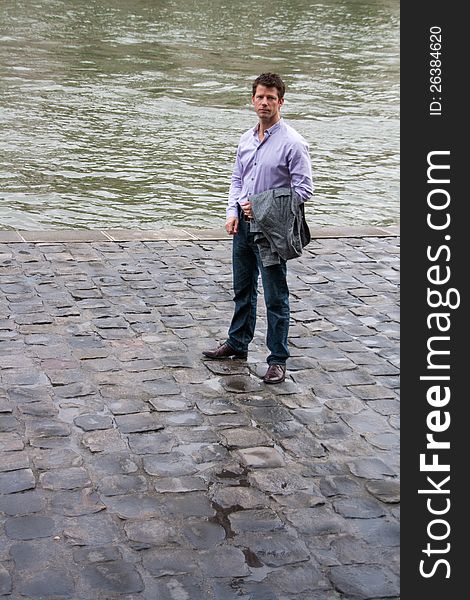 A man, with a sad expression, standing next to a canal. A man, with a sad expression, standing next to a canal.