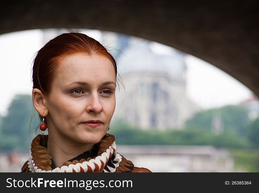A red-haired woman standing under an arch with the Notre Dame Cathedra in the background. A red-haired woman standing under an arch with the Notre Dame Cathedra in the background.