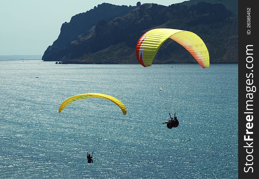 Paragliding in the blue sky above the sea and rocks