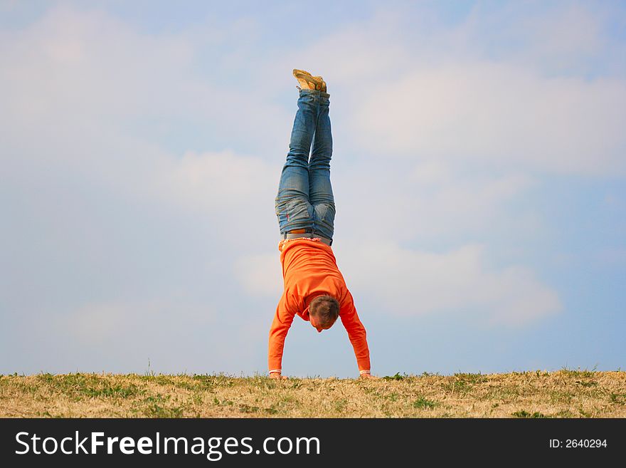 Man stand upside down against a cloudy sky