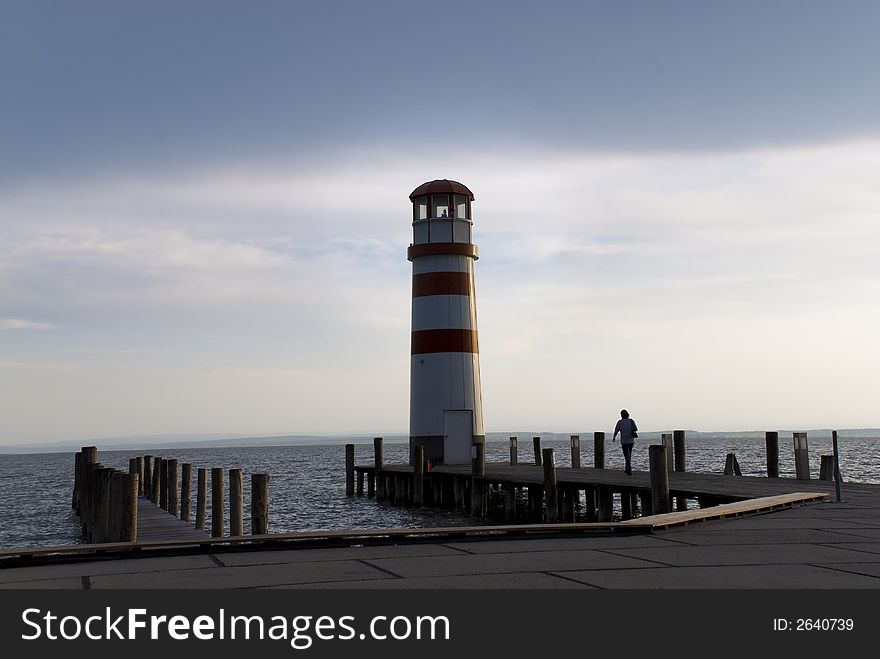 Lighthouse at an Austrian lake with a woman walking towards it. Lighthouse at an Austrian lake with a woman walking towards it