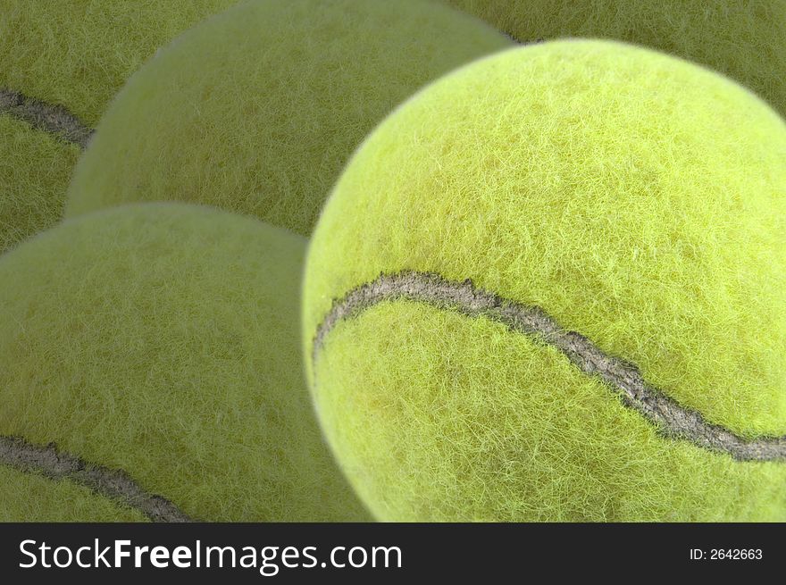 Tennis ball in foreground with more tennis balls as a darker background. Has clipping path for tennis ball