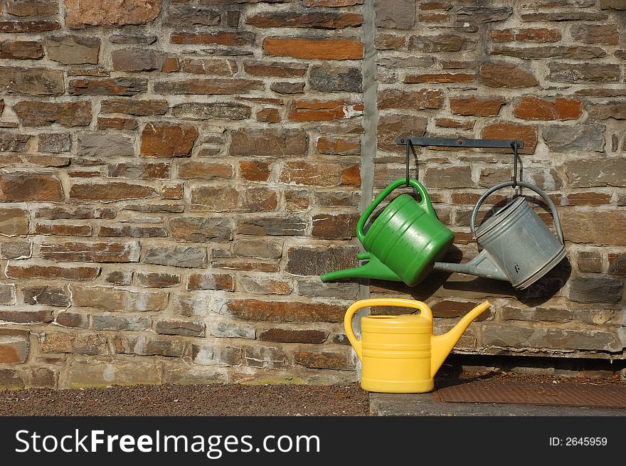 Three watering cans on the wall