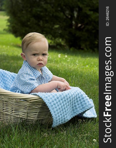 Image of beautiful toddler sitting in a basket in the grass. Image of beautiful toddler sitting in a basket in the grass