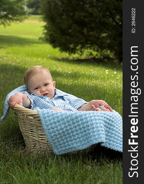 Image of beautiful toddler sitting in a basket in the grass. Image of beautiful toddler sitting in a basket in the grass