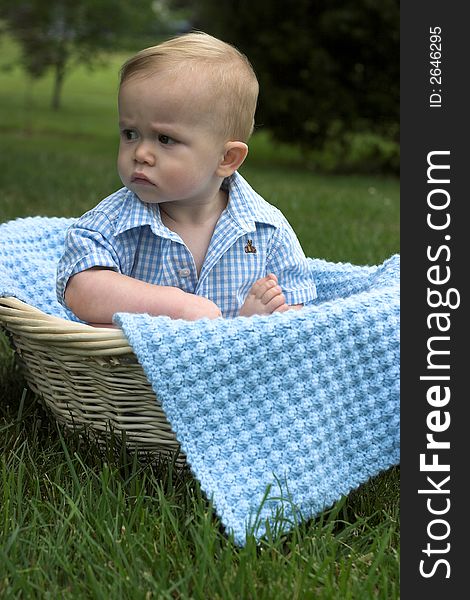 Image of beautiful toddler sitting in a basket in the grass. Image of beautiful toddler sitting in a basket in the grass