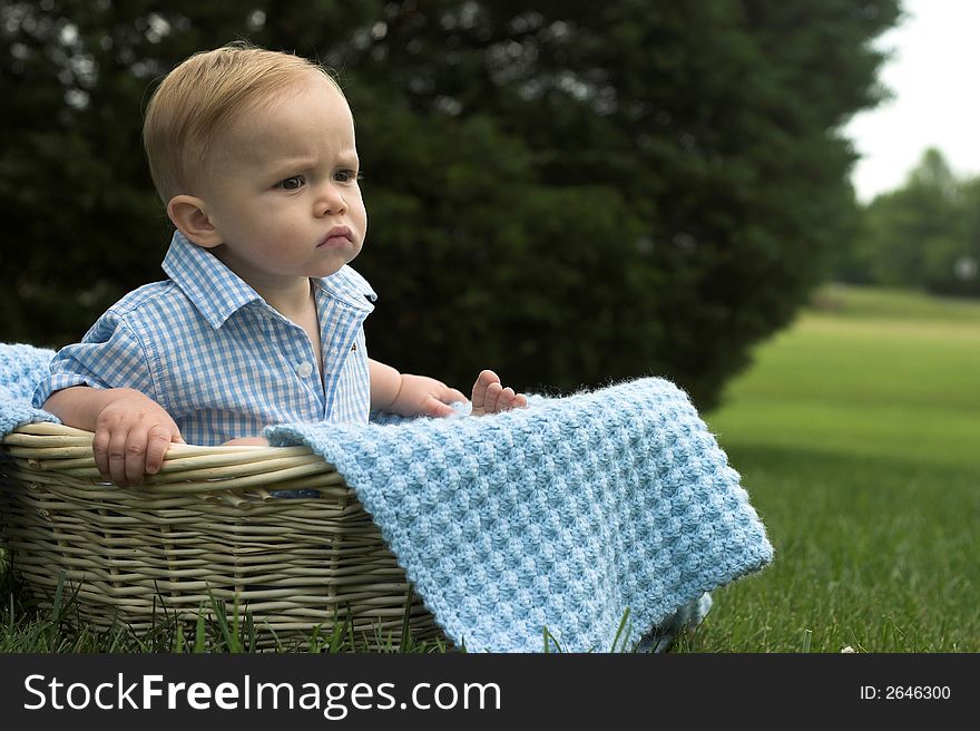 Image of beautiful toddler sitting in a basket in the grass. Image of beautiful toddler sitting in a basket in the grass