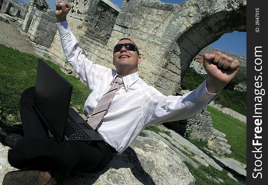 Smiling young businessman with laptop.