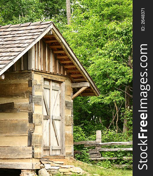 An old rustic building made of logs with a rail fence. An old rustic building made of logs with a rail fence