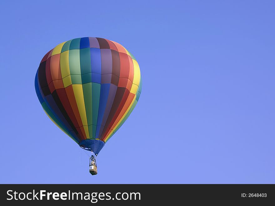 Here is a photo of a colorful hot air balloon floating peacefully in the sky with a beautiful blue backround