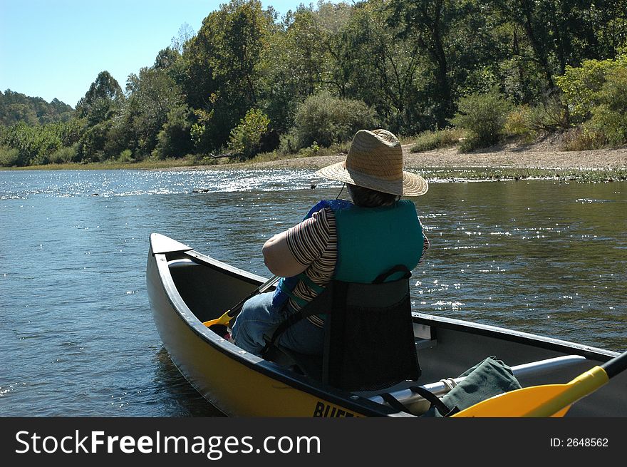 A woman floating down a river in a canoe. A woman floating down a river in a canoe