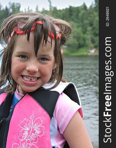 Young pretty girl wearing swimming goggles and life jacket at lake. Young pretty girl wearing swimming goggles and life jacket at lake