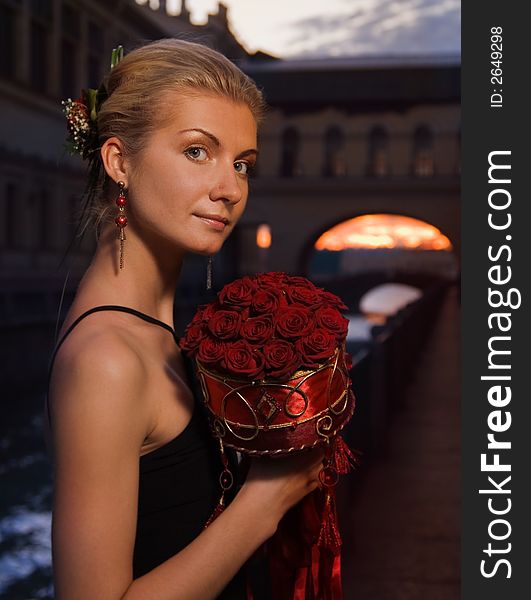 Beautiful blond girl with a boquet of roses at sunset time near the river