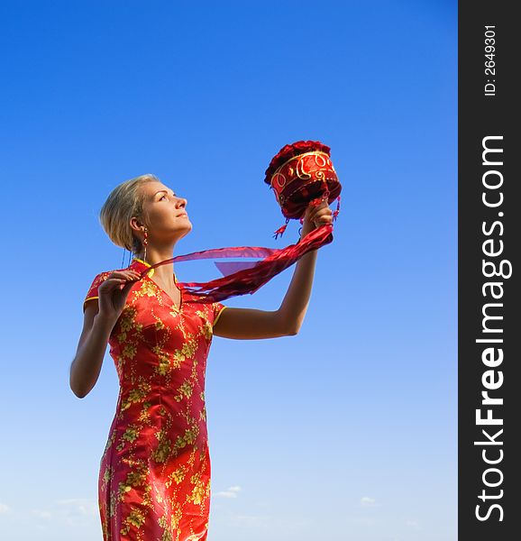 Beautiful blond girl with a bouquet of red roses over crystal clear blue sky