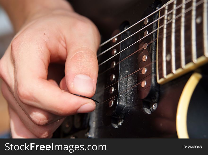 Close up of a hand playing with a pick on an electric guitar. Close up of a hand playing with a pick on an electric guitar