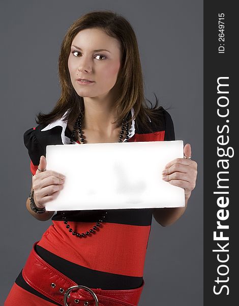 Attractive brunette wearing a red and black dress holding a white sign. Attractive brunette wearing a red and black dress holding a white sign