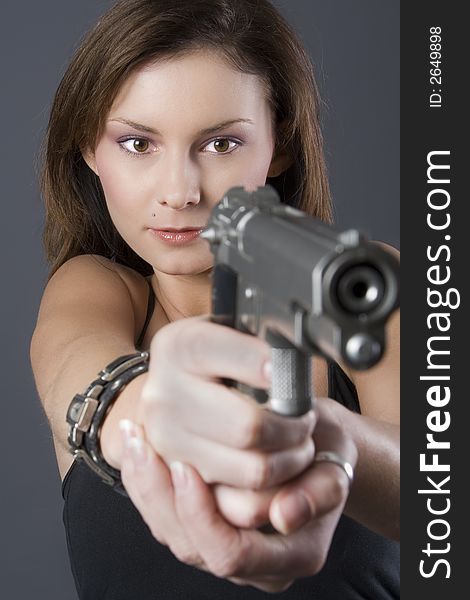 Attractive brunette pointing handgun towards camera. Attractive brunette pointing handgun towards camera