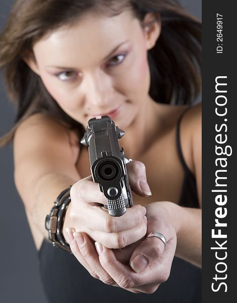 Attractive brunette pointing handgun towards camera. Attractive brunette pointing handgun towards camera