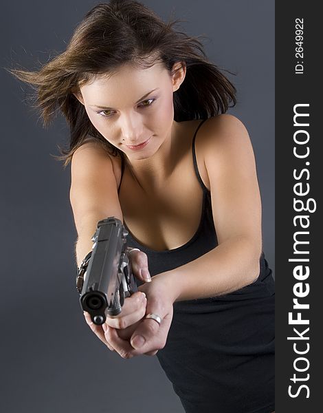 Attractive brunette pointing handgun towards camera. Attractive brunette pointing handgun towards camera