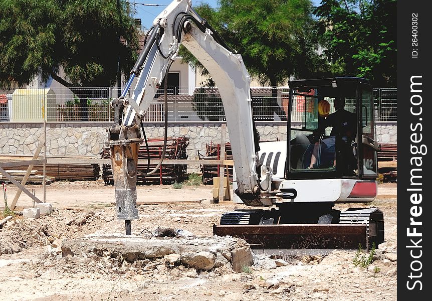 Excavator with hammer demolishes concrete structure for the foundation of new building