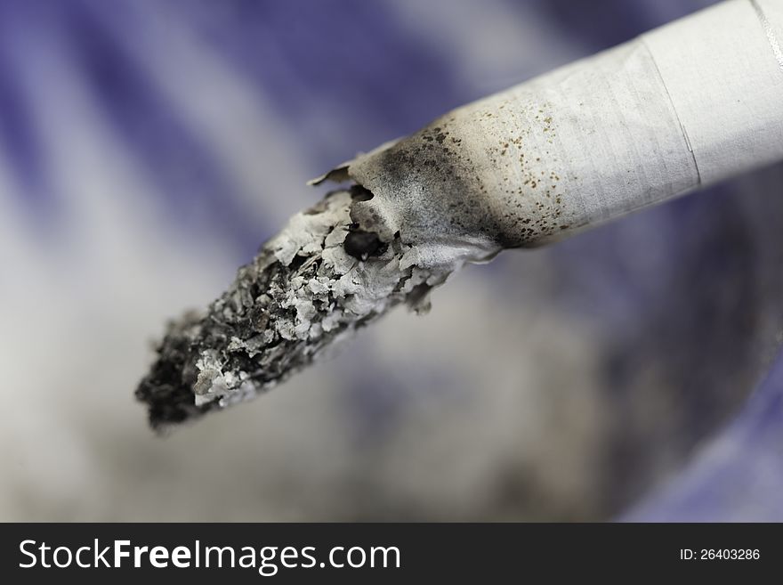 Close up of burning cigarette, on white and blue background. Close up of burning cigarette, on white and blue background