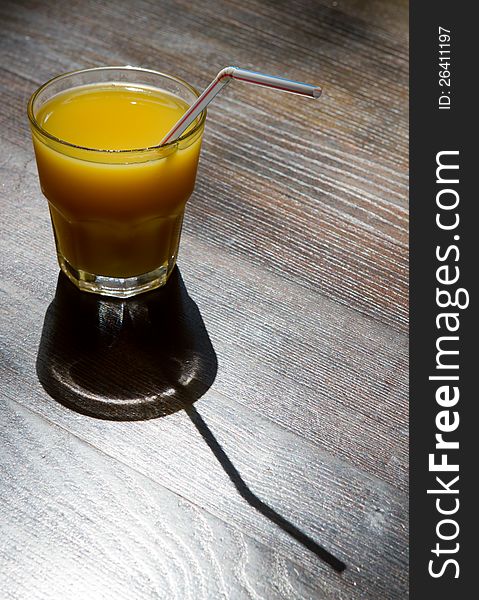 Glass of juice with tube on wooden table. Glass of juice with tube on wooden table